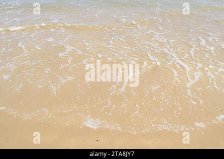 Nicht bearbeitetes Foto von friedlichem Wasserhorizont und Sandzusammensetzung. Nützlicher Sommerhintergrund mit Sandstrand mit Wasserrand Stockfoto