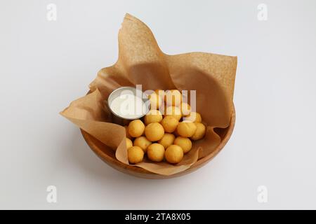 Salzkartoffelbällchen mit Aioli-Sauce auf Backpapier in Holzplatte auf weißem Hintergrund. Stockfoto