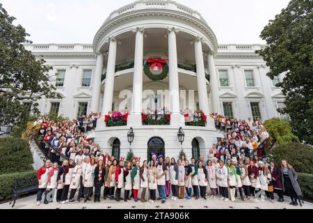 Washington, Usa. November 2023. Freiwillige posieren für ein Gruppenfoto auf dem Südportiko des Weißen Hauses nach Abschluss der Weihnachtsdekoration für das jährliche Weiße Haus am 28. November 2023 in Washington, DC. Das Thema ist „Magie, Wunderland und Freude“. 300 Freiwillige pro Woche nahmen an 98 Weihnachtsbäumen Teil. 34.000 Ornamente, 72 Kränze und etwa 142.000 Weihnachtslichter. Quelle: Katie Ricks/White House Photo/Alamy Live News Stockfoto