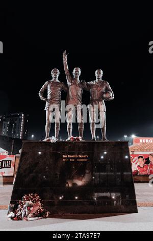 Trinity Statue von George Best, Bobby Charlton und Denis Law außerhalb von Manchester United FC at Night, Old Trafford, Manchester, UK Stockfoto