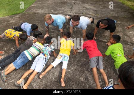 Puerto Princesa, Philippinen. November 2023. US-Marines mit der Marine Rotational Force-Südostasien, I Marine Expeditionary Force, führen einen Push-up-Wettbewerb mit Kindern im Bahay ni Nanay Maddalena Waisenhaus in Puerto Princesa, Palawan, Philippinen, am 19. November 2023 durch. Die Mitglieder des Dienstes mit MRF-SEA spielten Spiele und gaben den Kindern des Waisenhauses Essen aus, das von einem lokalen Cateringunternehmen bereitgestellt wurde, um Beziehungen zur örtlichen Gemeinde aufzubauen. MRF-SEA ist ein pazifisches Einsatzmodell der Marine Corps Forces, das den Austausch mit Fachexperten beinhaltet und Sicherheitsziele mit Alliierten A fördert Stockfoto