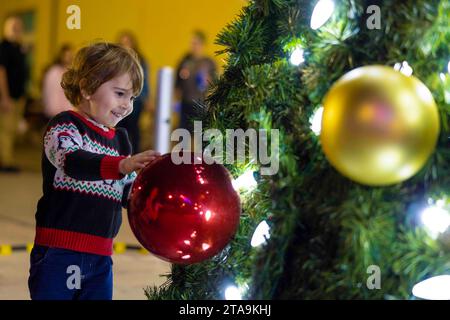 Yuma, Arizona, USA. November 2023. Während der jährlichen Weihnachtsbaumbeleuchtung an der Marine Corps Air Station (MCAS) Yuma, Arizona, berührt ein Kind ein Ornament auf dem Baum, am 17. November 2023. Jedes Jahr veranstaltet die Marine Corps Community Services eine Weihnachtsbaumbeleuchtung für die aktiven Dienstfamilien, die in MCAS Yuma stationiert sind, um die Weihnachtszeit zu beginnen. (Foto: CPL. Gideon M. Schippers) (Foto: © U.S. Marines/ZUMA Press Wire) NUR REDAKTIONELLE VERWENDUNG! Nicht für kommerzielle ZWECKE! Stockfoto