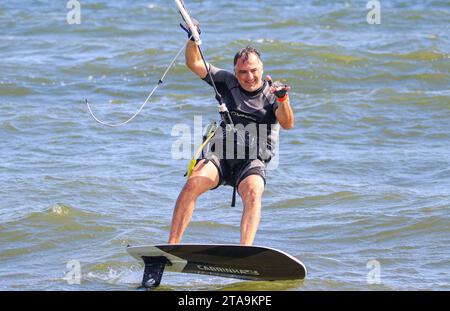 Gilgo, New York, USA - 13. August 2023: Ein Mann, der auf einem Kitesurf-Surfbrett auf einem Gewässer reitet. Stockfoto