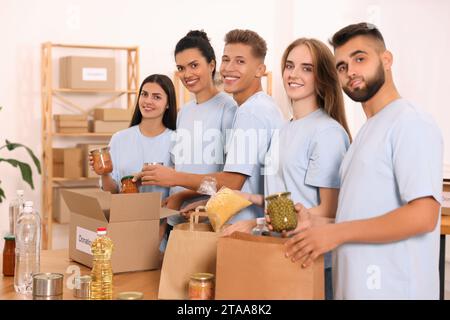 Porträt von Freiwilligen, die Lebensmittel am Tisch im Lager verpacken Stockfoto