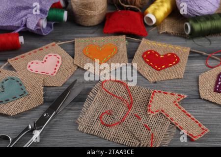 Buntfahnen aus Sackleinen-Stoff und Nähwerkzeuge auf Holztisch, Nahaufnahme Stockfoto