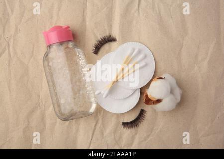 Flache Lagenkomposition mit Make-up-Entferner und falschen Wimpern auf zerknittertem Papier Stockfoto