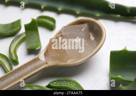 Aloe Vera Gel in Löffel und Pflanzenscheiben auf weißem, strukturiertem Hintergrund, Nahaufnahme Stockfoto