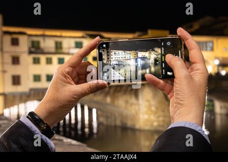 Frauenhände machen ein Foto von Ponte Vecchio auf ihrem iPhone. Stockfoto
