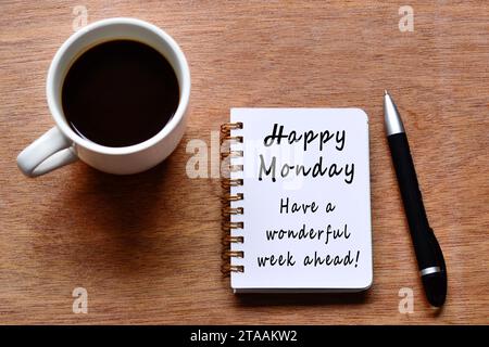 Happy monday mit Motivationszitat auf Notizbuch mit Kaffeetasse und Stift auf Holztisch. Stockfoto