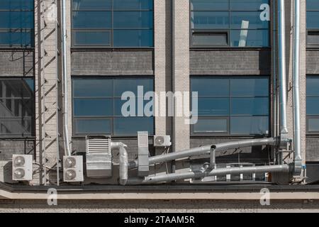 Lüftungsrohrsystem und externe Klimaanlagen an der Fassade eines Stadtgebäudes. Stockfoto