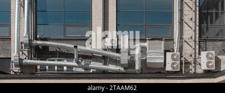 Lüftungsrohrsystem und externe Klimaanlagen an der Fassade eines Stadtgebäudes. Stockfoto