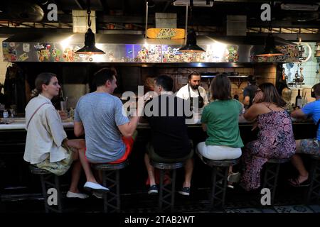 Gäste, die in einer offenen Küche in einem Grillrestaurant im San Telmo Market.Buenos Aires.Argentinien zu Mittag essen Stockfoto