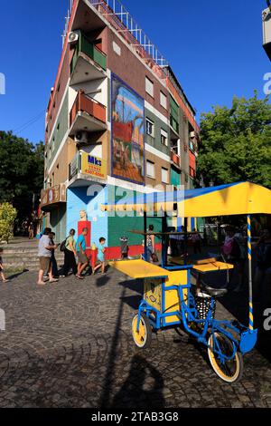 Ein farbenfrohes Gebäude und ein farbenfrohes Händlerdreirad in La Boca. Buenos Aires. Argentinien Stockfoto