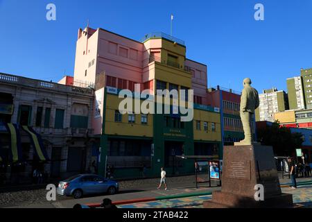 Die Statue von Benito Quinquela Martín am Fluss Riachuelo mit den bunten Gebäuden im Bezirk La Boca.Buenos Aires.Argentinien Stockfoto