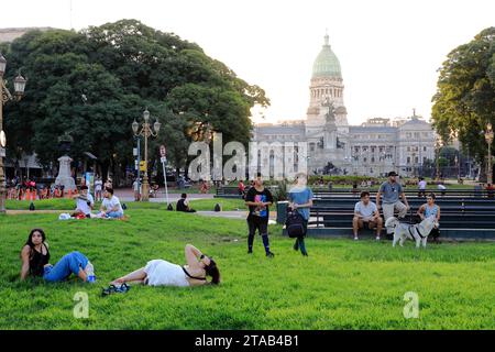 Die Leute entspannen sich in der Abenddämmerung auf der Plaza Mariano Moreno mit der Plaza del Congreso und dem Gebäude des Palastes des argentinischen Nationalkongresses im Hintergrund.Buenos Aires.Argentinien Stockfoto