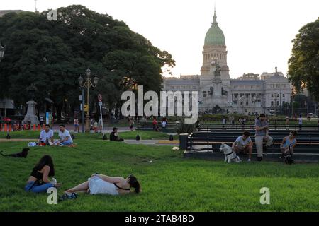 Die Leute entspannen sich in der Abenddämmerung auf der Plaza Mariano Moreno mit der Plaza del Congreso und dem Gebäude des Palastes des argentinischen Nationalkongresses im Hintergrund.Buenos Aires.Argentinien Stockfoto