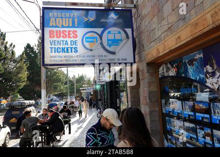 Ein Schild am Busschalter über dem Bürgersteig der Avenida del Libertador, der Hauptstraße von El Calafate mit Fußgängern und einem Straßencafé. Santa Cruz.Argentinien Stockfoto