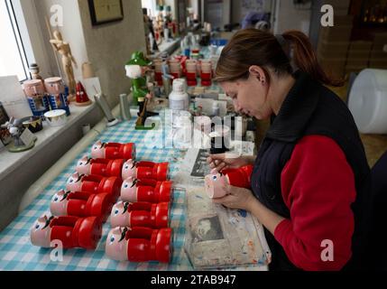 PRODUKTION - 27. November 2023, Sachsen, Seiffen: Carola Seifert malt Nussknacker in der Werkstatt des Holzspielzeugherstellers Markus Füchtner in Seiffen. Im Jahr 1870 soll Füchtners Ur-Ur-Großvater die ersten Erzgebirge-Nussknacker hergestellt haben, die heute neben Rauchern und Pyramiden auf der ganzen Welt für das Erzgebirge stehen. Das Handwerk setzt die alte Tradition fort und hat nun zum ersten Mal einen Mini-Nussknacker ins All geflogen. Der Nussknacker Wilhelm aus dem Erzgebirge ist nun nach seiner Reise ins Weltall wieder auf der Erde. Wilhelm wurde auf die International Space S gestartet Stockfoto