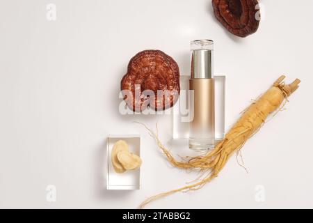 Werbeszene für Produkte mit Inhaltsstoffen aus seltenen Kräutern. Eine braune Flasche ohne Etikett auf transparentem Podium, verziert mit Ginseng-Wurzel und Lingzhi Stockfoto