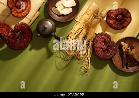 Foto für die Arzneimittelwerbung. Einige seltene Kräuter dekoriert, frische Ginseng-Wurzeln, rote Ginseng-Wurzeln und ganoderma-Pilze auf grünem Hintergrund Stockfoto