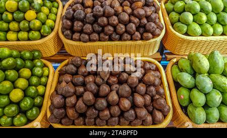 Eine Sammlung frischer Mangos, Schlangenfrüchte und Orangen auf einem Stapel Obstregale in einem Supermarkt Stockfoto
