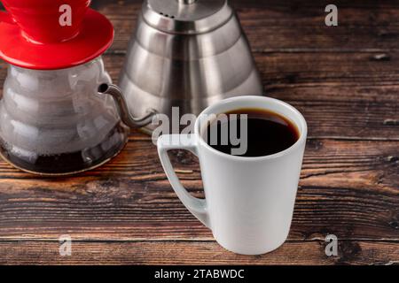 Eine Tasse Kaffee und eine dritte Generation gießen Sie Kaffee-Brühgeräte auf Holzboden Stockfoto