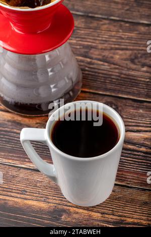 Eine Tasse Kaffee und eine dritte Generation gießen Sie Kaffee-Brühgeräte auf Holzboden Stockfoto