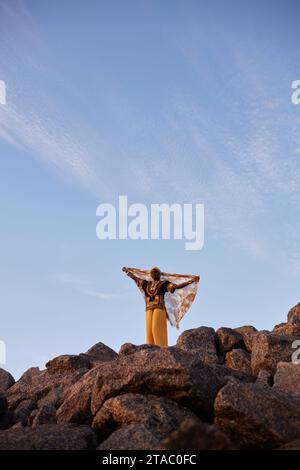 Weitwinkelporträt einer schwarzen jungen Frau, die auf dem Berg steht und mit Schleier tanzt, Kopierraum Stockfoto