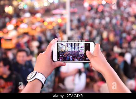 New York, USA - 10. Juni 2018: Eine Frau macht ein Foto auf seinem iPhone am Times Square in New York. Stockfoto