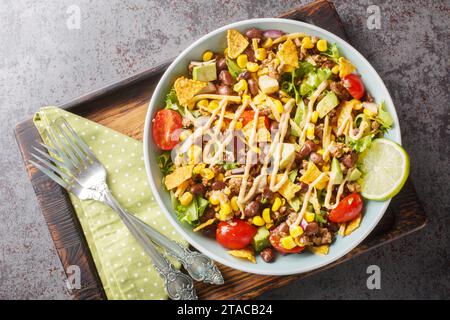 Der leichte Taco-Salat wird mit gewürztem Hackfleisch, knusprigem Salat, Gemüse, Käse und geschmackvollen Toppings aus der Nähe auf dem Teller auf dem Tisch zubereitet. Horizont Stockfoto