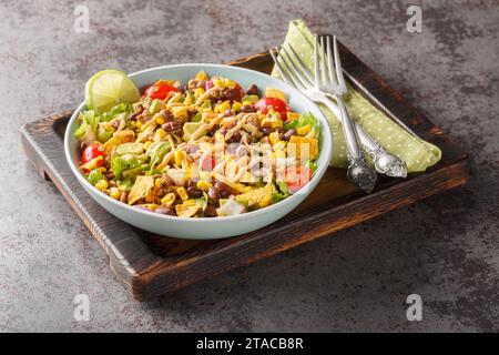 Der leichte Taco-Salat wird mit gewürztem Hackfleisch, knusprigem Salat, Gemüse, Käse und geschmackvollen Toppings aus der Nähe auf dem Teller auf dem Tisch zubereitet. Horizont Stockfoto