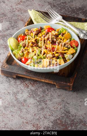 Mexikanischer Taco-Salat mit Hackfleisch, Gemüsesalsa, Käse mit cremiger Soße in Nahaufnahme auf einem Teller auf dem Tisch. Vertikal Stockfoto