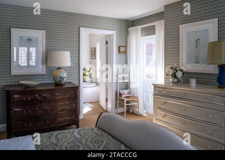 Gemusterte Tapeten und Truhen mit Netzvorhängen am französischen Fenster in einem Haus im Arts and Crafts Stil der 1930er Jahre. Hove, East Sussex, Großbritannien. Stockfoto