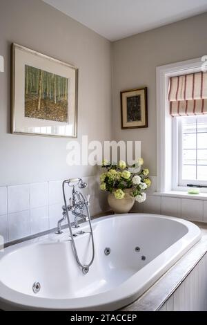 Blumen in Vase auf Jacuzzi Bad umgeben in 1930s Arts and Crafts Stil Haus. Hove, East Sussex, Großbritannien. Stockfoto