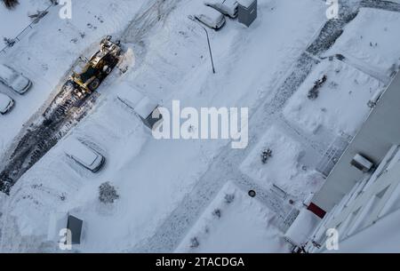 Der Traktor reinigt Schnee von der Straße und lädt ihn in den Lkw. Schneeräumung nach Schneefall und Schneestürmen. Stockfoto