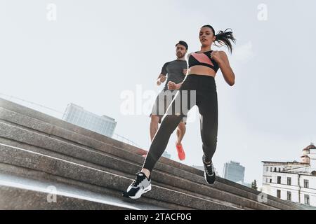 Auf der Treppe trainieren. Niedriger Blickwinkel auf ein junges Paar in Sportkleidung, das zusammen die Treppe hinunterläuft Stockfoto