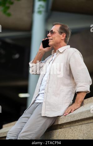 Mann posiert auf der Straße und sieht mit seinem Handy aus. Stockfoto