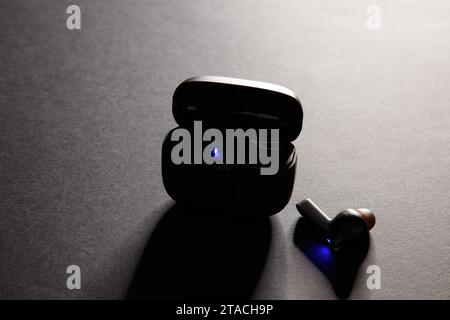 Eine Studioaufnahme eines schwarzen jbl Wireless bluetooth-Ohrhörers vor einem dramatisch beleuchteten schwarzen Hintergrund Stockfoto