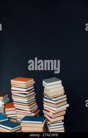 Viele Stapel alter Lehrbücher in einer Bibliothek mit schwarzem Hintergrund Stockfoto