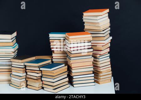 Viele Stapel alter Lehrbücher in einer Bibliothek mit schwarzem Hintergrund Stockfoto