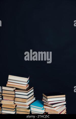 Viele Stapel alter Lehrbücher in einer Bibliothek mit schwarzem Hintergrund Stockfoto