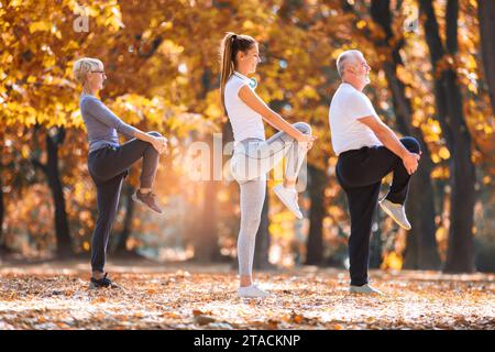 Senior-Mann und Frau und junge Instruktorin trainieren an der frischen Luft. Outdoor-Aktivitäten, gesunder Lebensstil, starke Körper, fitte Figuren. Stilvoll, mobil Stockfoto