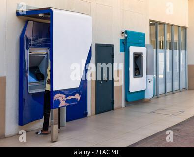 afroamerikanischer junger Mensch, der einen Geldautomaten in einem Einkaufskomplex benutzt Stockfoto