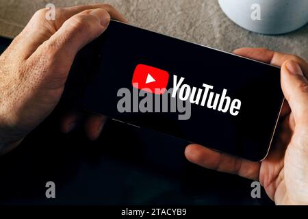 YouTube-Logo auf dem Smartphone-Bildschirm. Mann, der ein Smartphone hält, während die App geöffnet ist. Video-Streaming-Anwendung auf Mobiltelefon. Stockfoto