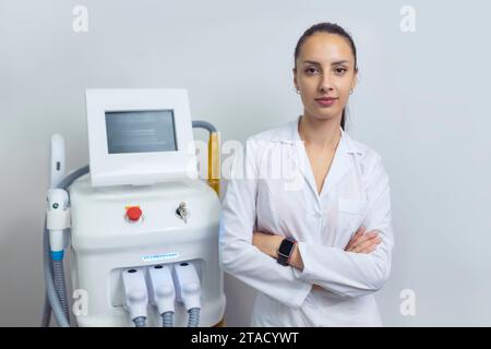 Der Kosmetikarzt steht neben dem Laser-Haarentfernungsgerät Stockfoto