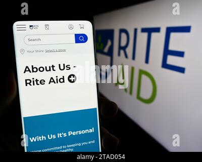 Person mit Smartphone und Webseite der US-Drogerie Rite Aid Corporation vor dem Logo. Konzentrieren Sie sich auf die Mitte des Telefondisplays. Stockfoto