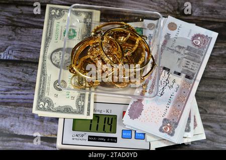 Kairo, Ägypten, 9. November 2023: Stapel Gold auf einer digitalen Ming-Heng-Skala in Gramm mit ägyptischen Pfund und US-Dollar-Bargeld-Banknoten Stockfoto