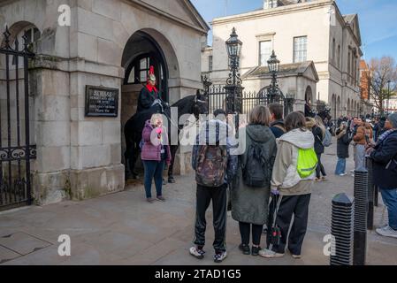 Touristen posieren für Fotos mit King's Life Guard, Mitglied der Mounted Household Cavalry, auf dem Pferd vor der Horse Guards Parade in Whitehall, London Stockfoto