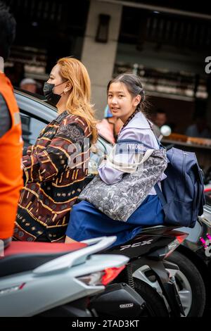 Ein thailändisches Schulmädchen sitzt hinten in einem Motorradtaxi, das durch die geschäftigen Straßen von Pattaya City, Bangkok, fährt. Stockfoto