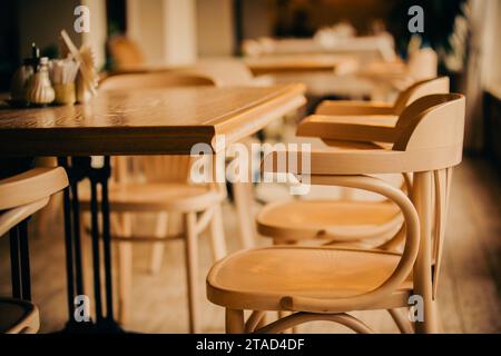 Leeres Café-Innere am Abend. Holztische und elegante Holzstühle. Restaurant-Ausstattung. Balken nach Schließen. Ruhen Sie sich in einem Café aus. Stockfoto